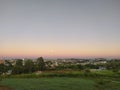 Blue sky with shades of red, yellow and orange at sunset and some trees in the city at dusk