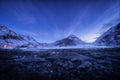 Blue sky with stars rocky beach and snow covered mountains Royalty Free Stock Photo