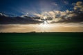 In the blue sky the sun rays shine over a green field Royalty Free Stock Photo