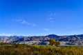 Blue sky with tiny clouds above mountain peaks and autumn valley