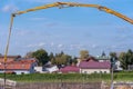 Blue sky with tiny clouds framed by the yellow arm of a concrete pump. Pouring concrete on the construction site of a bridge.