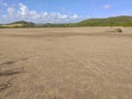 Panoramic photo of dry salt pans of ocher color. Blue sky with tropical clouds and mountains with vegetation. Martinique, French