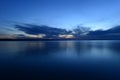 Blue sky in the twilight glow from behind clouds over the azure calm surface of the water Royalty Free Stock Photo