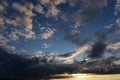 Blue sky in white cirrus clouds in sunlight from a dark cloud in the evening at sunset Royalty Free Stock Photo