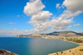 Blue sky and white clouds above the Bay on the Black sea in the Crimea, on the beach in Sudak. Royalty Free Stock Photo