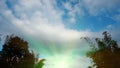 Blue sky with white clouds with golden sunlight on green treetops, natural beauty taken from the garden