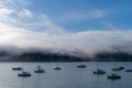 Blue sky, white clouds, mist & aquamarine seas at Akaroa Harbor. Anchored are fishing boats & sailboats, along the Port at Akaroa Royalty Free Stock Photo