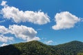 A blue sky with white clouds over the hills covered with forest Royalty Free Stock Photo