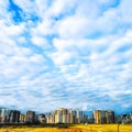 Blue sky with white clouds and residential buildings on the horizon