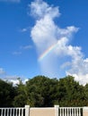 Blue sky and white clouds with small piece of rainbow over the tropical garden. Royalty Free Stock Photo