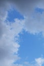 A blue sky with white clouds and tree branches below Royalty Free Stock Photo