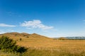 Blue sky with white clouds, trees, fields and meadows with green grass, against the mountains. Composition of nature Royalty Free Stock Photo