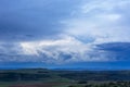 Blue sky and white cumulus clouds over green landscape after sunset