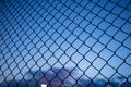 Blue sky through wire mesh fence. Blur background, close up view of link cage, wallpaper. Royalty Free Stock Photo