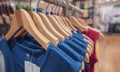 Blue sleeveless shirt on wooden hanger hanging on rack in clothing store for sale. Fashion retail shop inside shopping center. Royalty Free Stock Photo