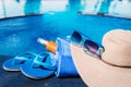 Blue slippers with sunscreen cream, towel, straw hat and sunglas Royalty Free Stock Photo