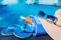 Blue slippers with sunscreen cream, towel, straw hat and sunglas Royalty Free Stock Photo