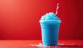 Blue slush drink in clear plastic cup with red striped straw. Frozen beverage with ice crystals on red surface against solid red Royalty Free Stock Photo