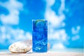 Blue slush ice in glass on sea beach background