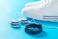 Blue smart bracelet, over-ear headphones and white sneakers on blue background. Sports style. Royalty Free Stock Photo