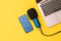 Blue and blue smartphone microphone near the laptop on a yellow background. The concept of workplace organization Royalty Free Stock Photo