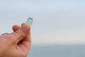 Blue smooth glass from the sea in the hand of a man against the sky