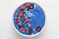 Blue smoothie bowl with fresh and frozen berries, banana and coconut on white marble table. healthy breakfast Royalty Free Stock Photo