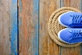 Blue sneakers shoes on a rope spiral, on a wooden weathered terrace. Yacht style concept.