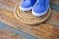 Blue sneakers shoes on a rope spiral, on a wooden weathered terrace. Yacht style concept.