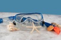 Blue snorkel mask with shells on the sand with blue background Royalty Free Stock Photo