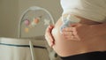 Blue socks for a baby boy in pregnant woman`s hand against her belly. Waiting for a future child. Copy space, close up Royalty Free Stock Photo