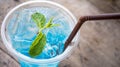 Blue soda cocktail with peppermint on top at wooden table