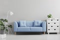 Blue sofa between white lamp and cabinet in grey living room int