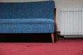 Blue sofa and white radiator resting on red carpet in waiting room Royalty Free Stock Photo