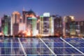 Blue solar cell panels, blurred city skyline illuminated at night