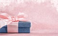 Blue sparkling gift box with pink ribbon on pink background