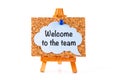 Blue speech bubble with phrase Welcome to the team on a corkboard on a wooden easel