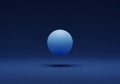 A blue sphere floats in a dark blue environment, casting a soft shadow below. The Royalty Free Stock Photo