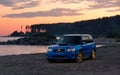 Blue sport wagon on the lake beach at sunset