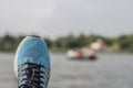 Blue sports shoe with a blurred view of a lake and a boat