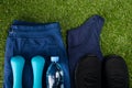 Blue sportswear, black sneakers, dumbbells and a bottle of water, against the background of grass Royalty Free Stock Photo