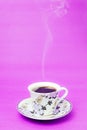 Blue stamped mug with steaming coffee. Soft smoke. Purple background.