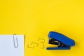 Blue stapler with metal staples and paper clip on yellow background. Top view. Copy, empty space for text. Minimalistic concept Royalty Free Stock Photo