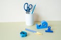 Blue stationery. Colored pencil, pen, scissors, clip, tape measure, tape dispenser on desk. white ivory background