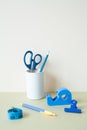 Blue stationery. Colored pencil, pen, scissors, clip, tape measure, tape dispenser on desk. white ivory background