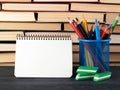 blue stationery glass with multi-colored wooden pencils, open spiral notebook