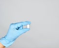 blue sterile gloved hand holding a white pill Royalty Free Stock Photo