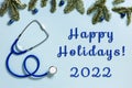 Blue stethoscope with green Christmas tree branches Medical background blue colored with text Happy Hollidays 2022