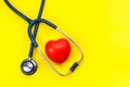 Blue stethoscope and red heart shape on yellow background. For c Royalty Free Stock Photo