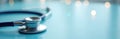 Blue stethoscope rests on a reflective teal surface. Blurred lights create a soft, ethereal backdrop. This represents medical Royalty Free Stock Photo